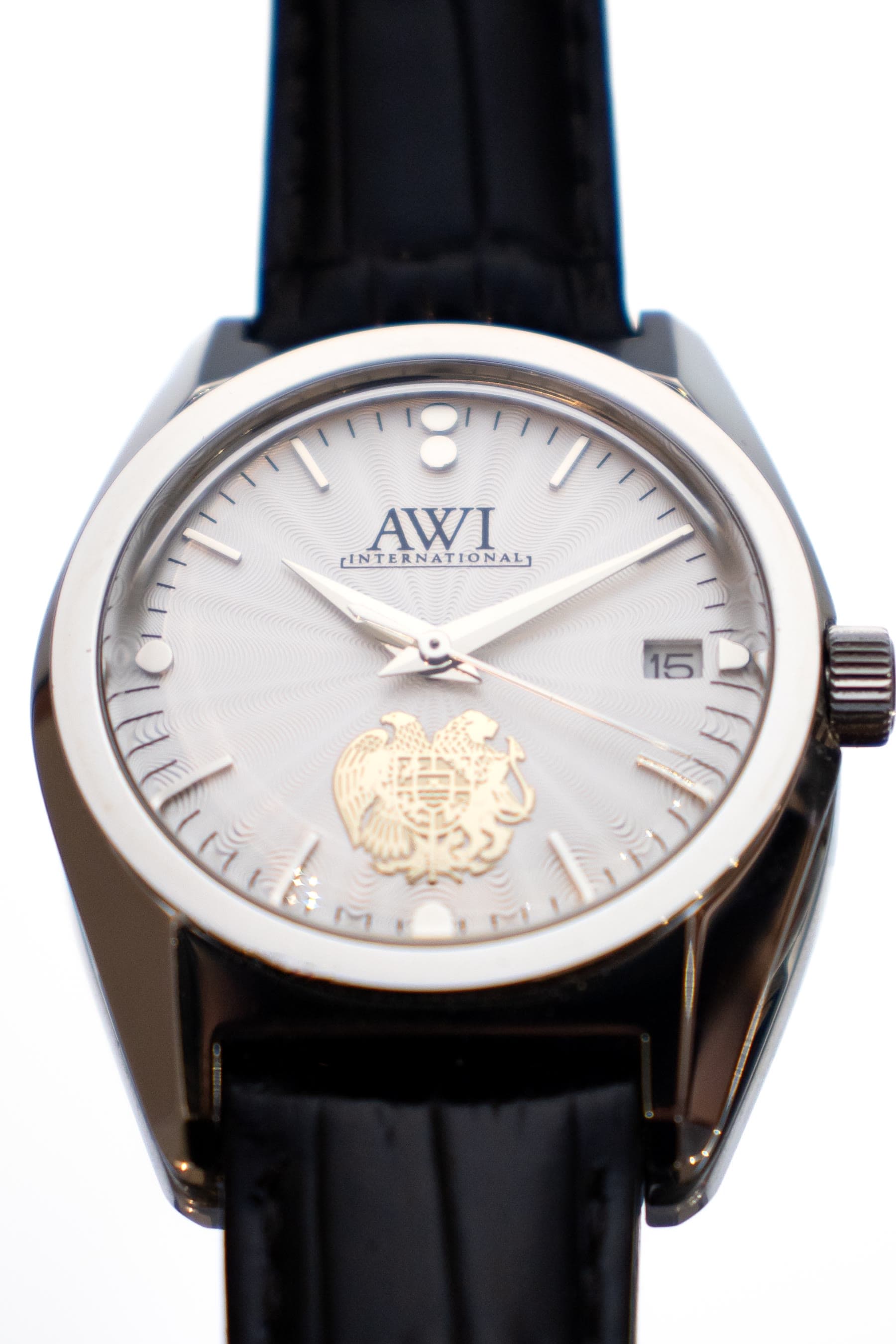 An AWI watch with a coat of arms on the dial and a black leather strap
