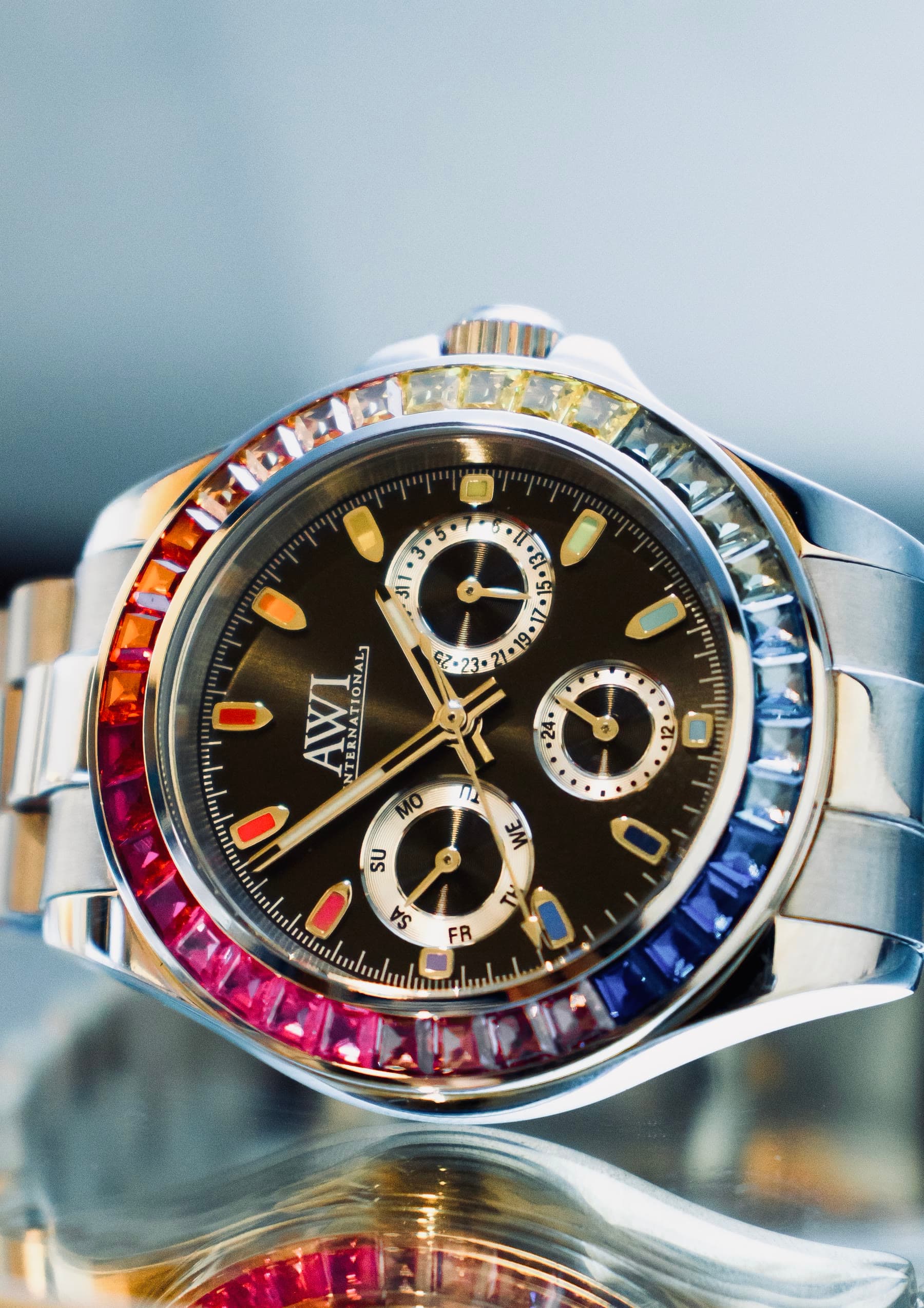 An AWI watch with a rainbow bezel and a black dial