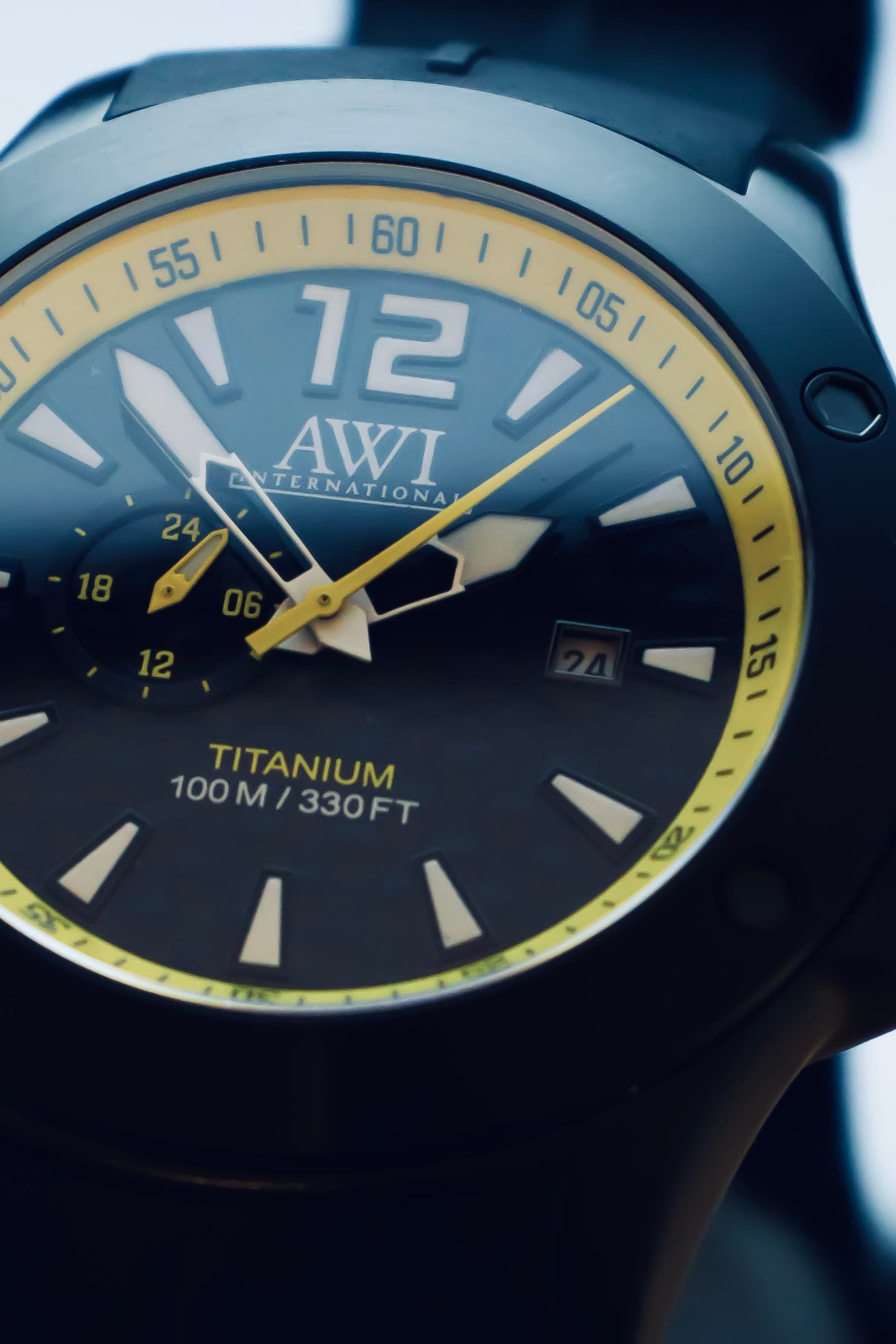 A titanium AWI watch with yellow accents on a dark background