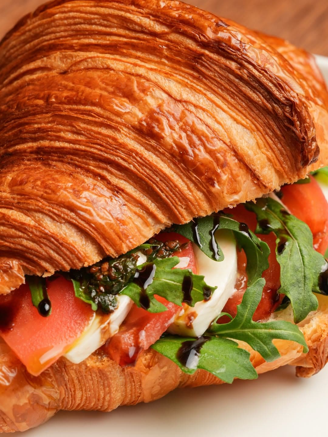 A croissant sandwich with mozzarella, tomatoes and rocket under sauce