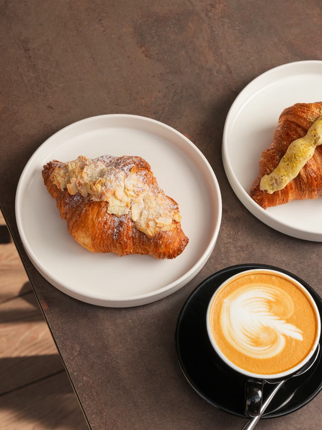 Croissants on white plates beside a latte art coffee