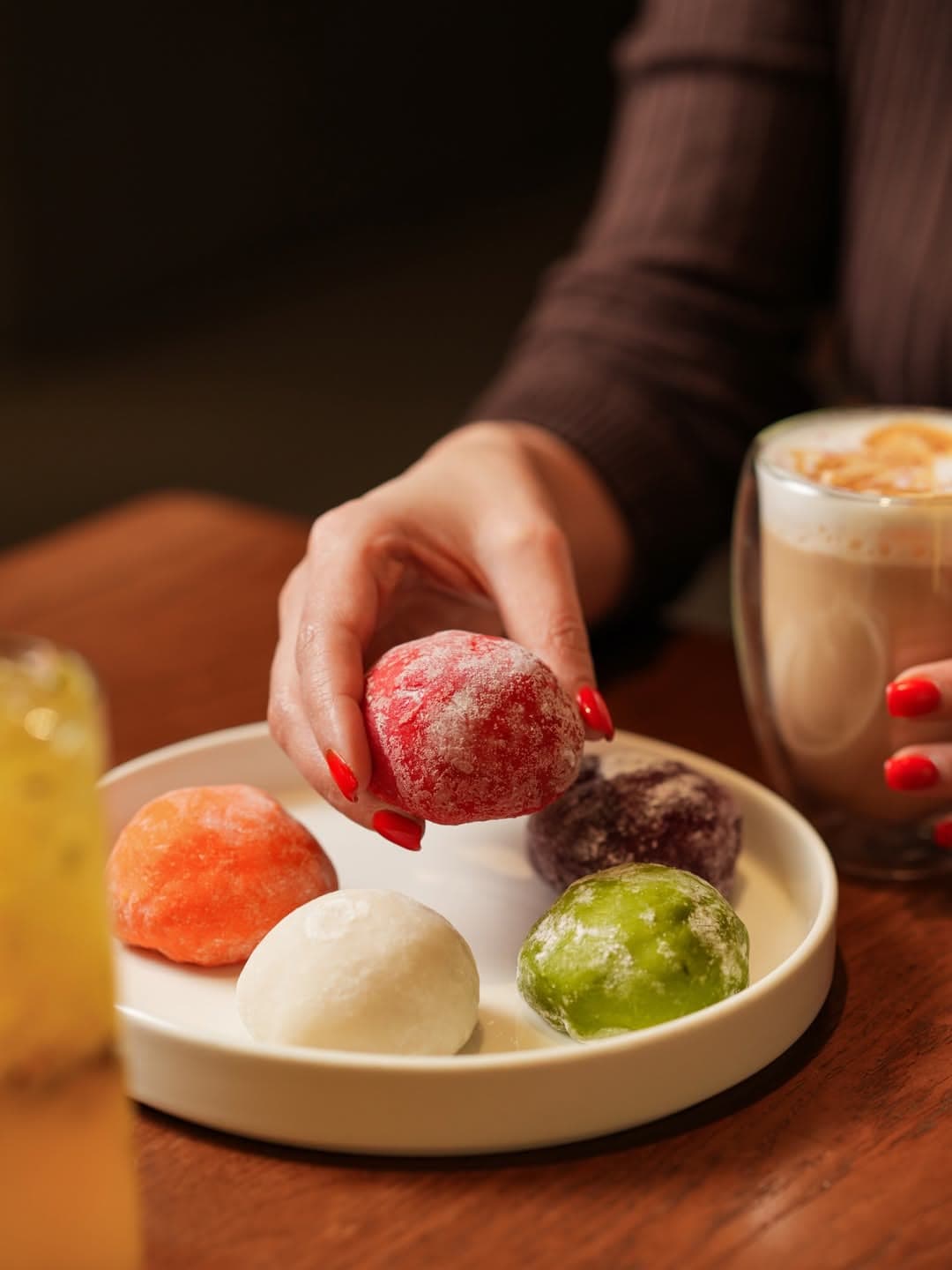 Mochi desserts on a ceramic plate with drinks on the table
