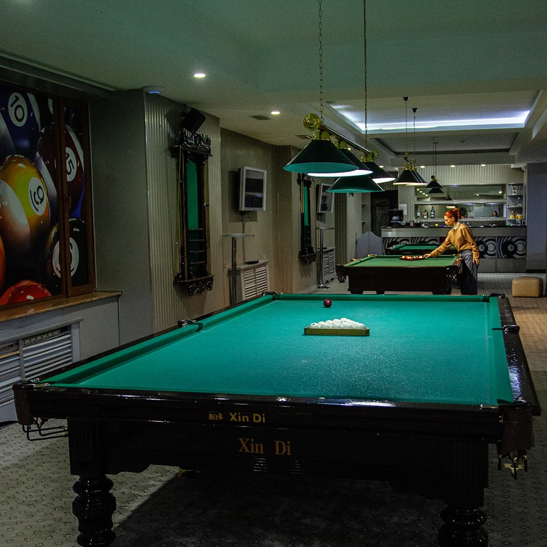 The hotel billiard room: a table under low-hanging lamps