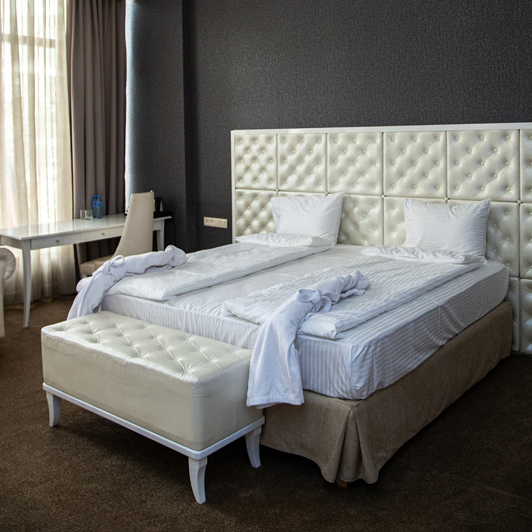 A room with a king bed, quilted headboard and white linen