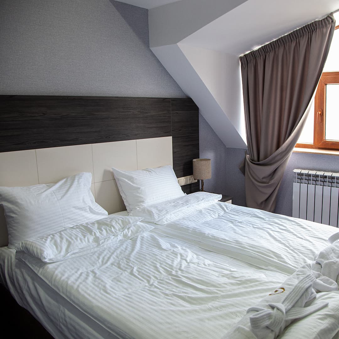 An attic room with a white bed under the roof slope