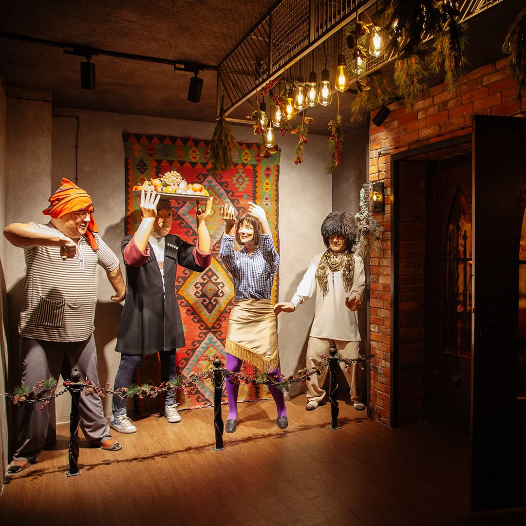 The hotel photo zone: guests in traditional Armenian costumes by a carpeted wall