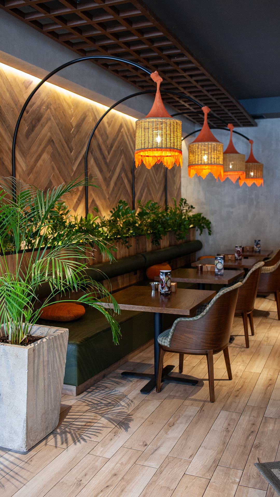 A contemporary restaurant hall with woven pendant lights and greenery
