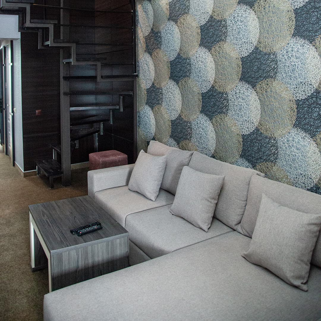 The living room of a suite with a light corner sofa