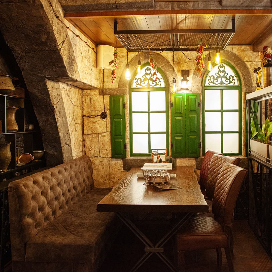 A private nook of the restaurant with green shutters and leather sofas
