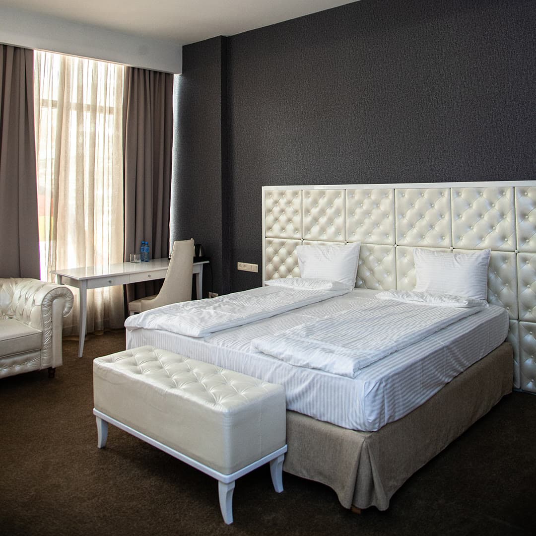 A twin room with a quilted headboard and a desk chair