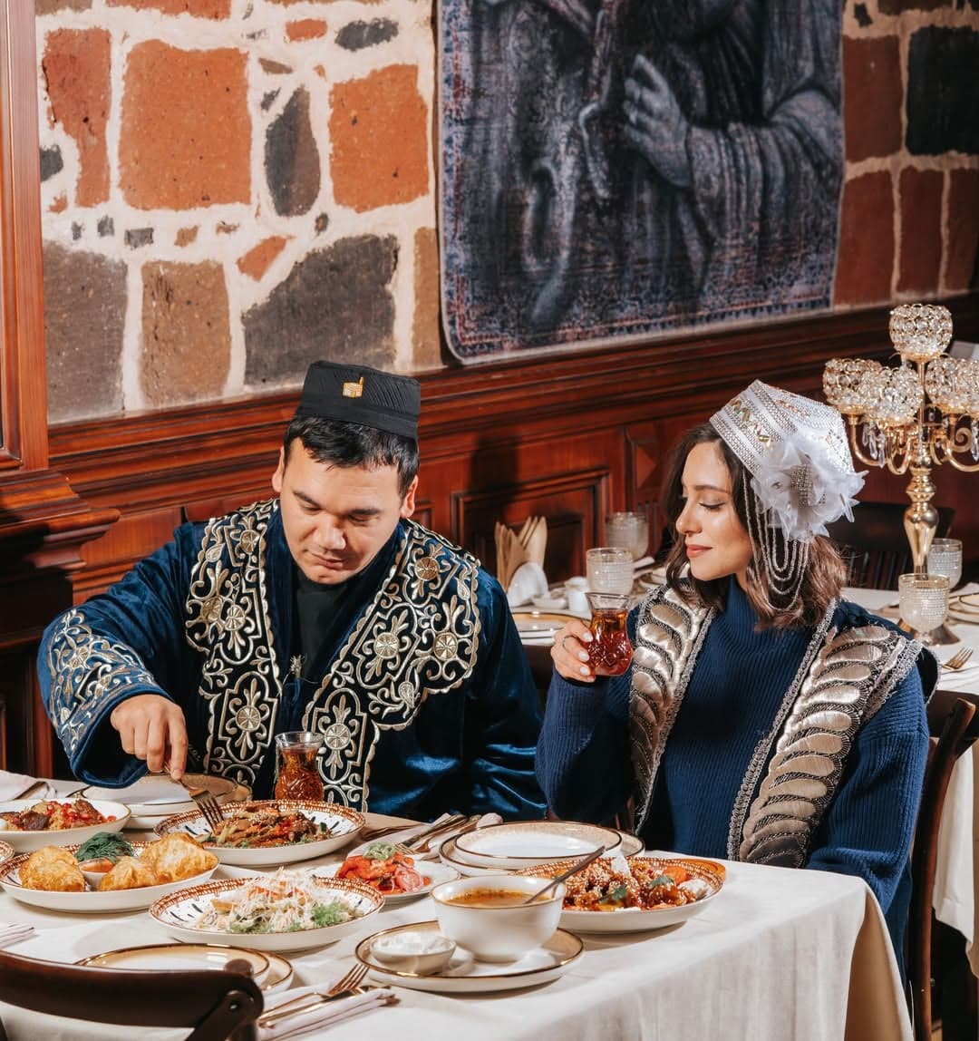 Guests in traditional Uzbek costumes at a laid table